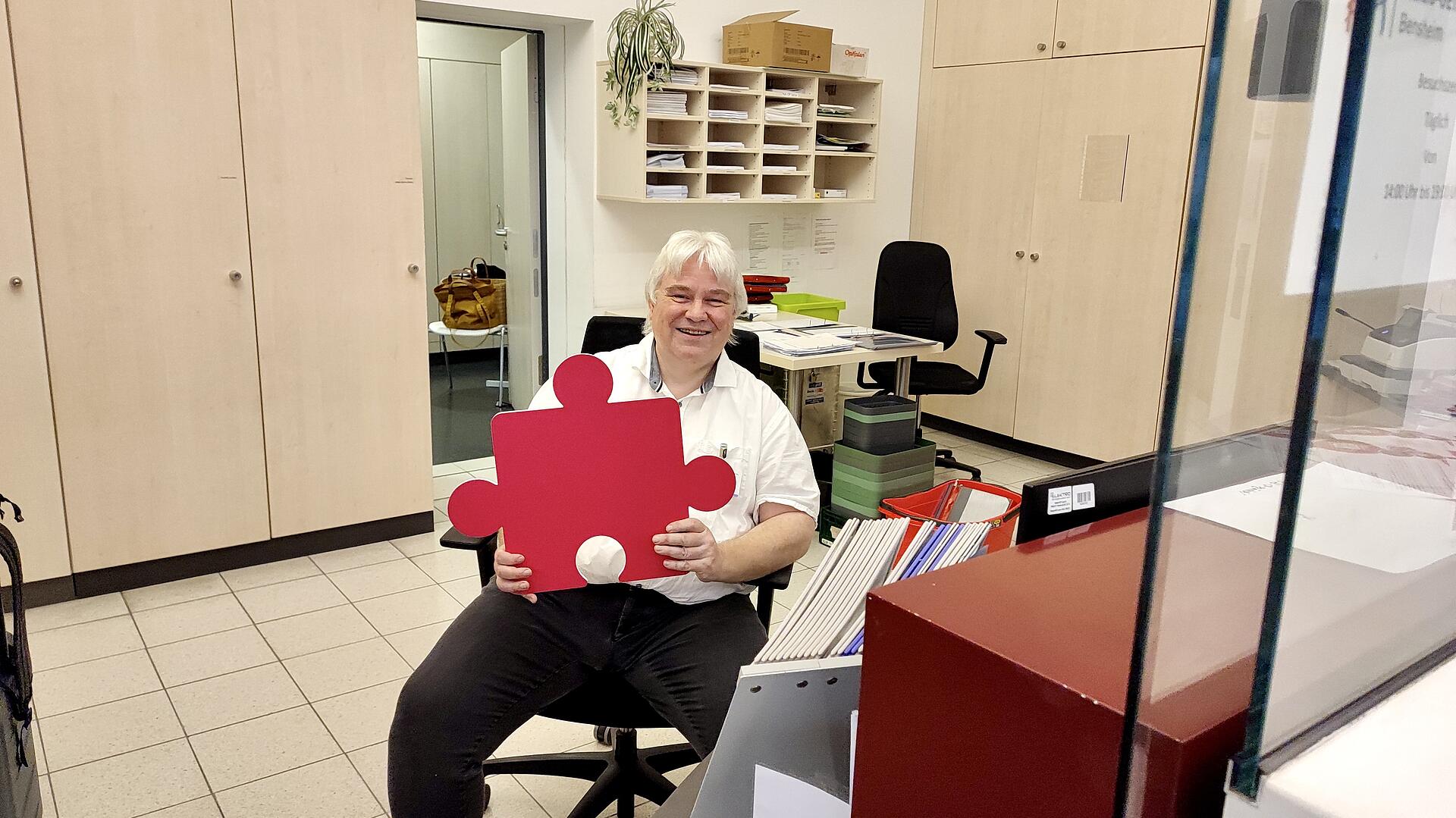 Empfangsmitarbeiter Matthias Zeiß mit Puzzleteil in der Hand