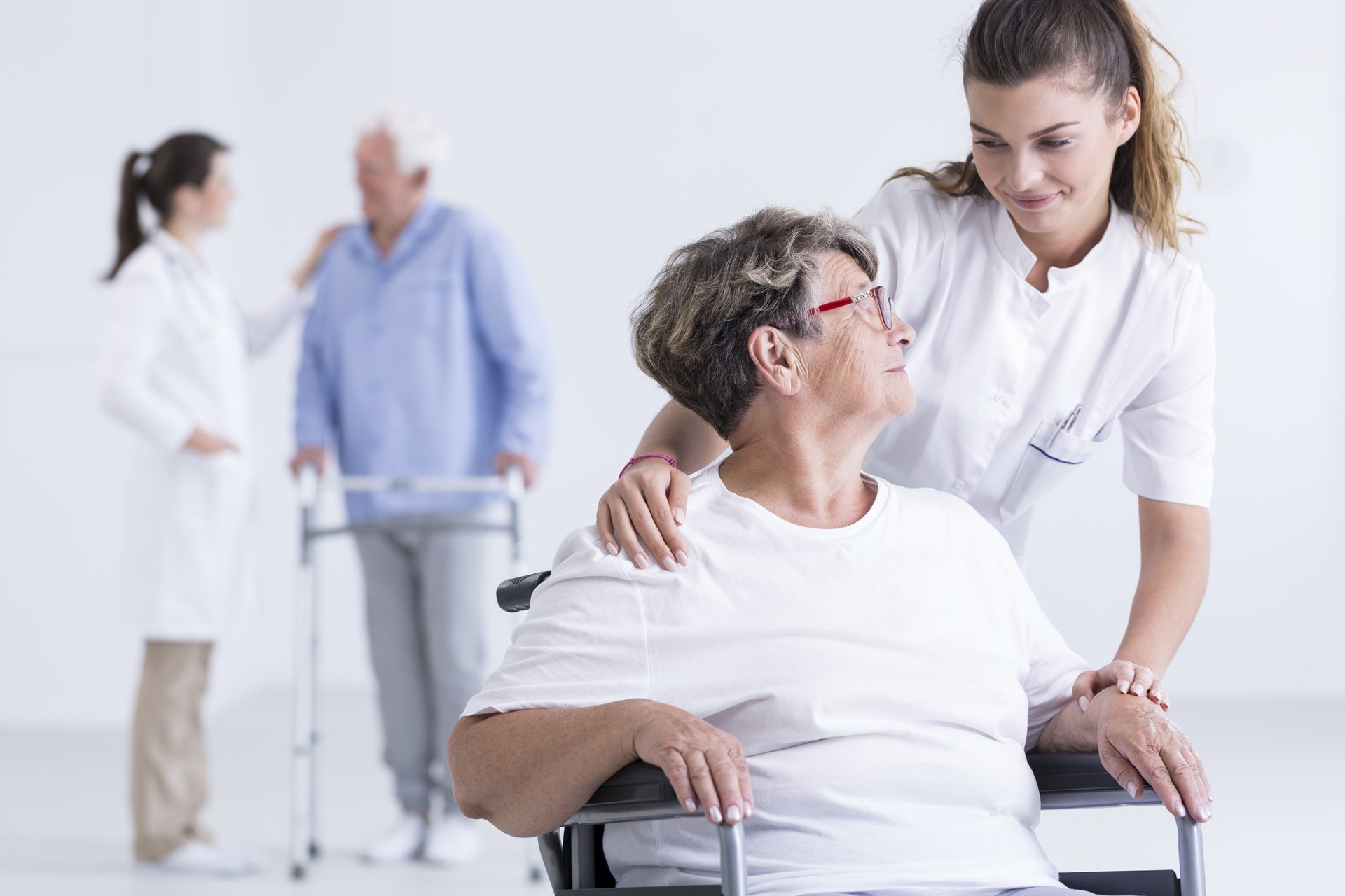 Pflegerin hilft Frau im Rollstuhl